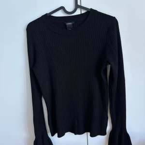 Tröja  - Ribbad tröja med trumpetarmar. Finns en liten fläck på ena armen (se bild).