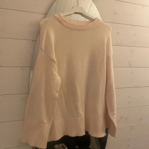 Ljusbeige/vit stickad tröja - Supermysig ljusbeige stickad tröja med bred ribbad kant vid hals, ärmslut och nederkant. Tröjan har en avslappnad passform och långa ärmar, perfekt för kyliga dagar. Enkel och stilren design som är lätt att matcha. Oanvänd.