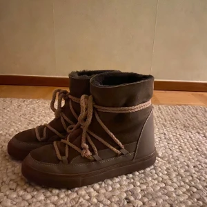 Bruna Inuikii boots med snörning - Säljer ett par bruna Inuikii boots med grov snörning och rund tå. Skorna har en kombination av mocka och skinn, samt en varm fodrad insida. Säljer eftersom de va för stora. Kan tänka mig sänka priset lite 
