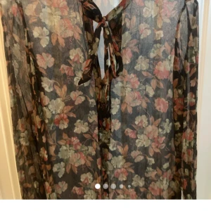 Ralph Lauren Blommig blus i höstfärger med knyt - Ralph Lauren siden  med blommigt mönster i dova hastiga färger. Blusen har långa ärmar och snygg knytning vid halsen. Perfekt för dig som gillar romantisk och bohemisk stil. Perfekt på kontoret. Storlek 6 passar mig som är M men är luftig.