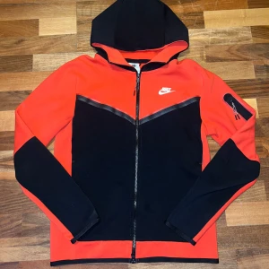 Nike tech fleece Röd/Svart storlek S - Röd/Svart Nike tech fleece i mycket bra skick, har max används 2-3 gånger. Ljusen gör så att det ser orange ut. Om ni vill snacka om priset det bara att skriva.