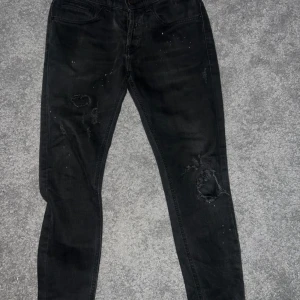 Svarta jeans från Dondup - Svarta jeans från Dondup som lutar mer åt de tighta hållet på passformen och slitna detaljer på benen. Riktigt fräsha för nu mot vintern.