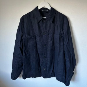 Mörkblå overshirt från Zara, M - Stilren mörkblå overshirt från Zara med klassisk krage och knäppning framtill. Modellen har två bröstfickor och är tillverkad i en blandning av polyester och bomull. Perfekt för lager-på-lager och enkel att matcha med andra plagg. 3U8