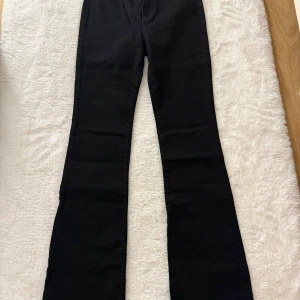 Svarta bootcut jeans - Snygga svarta jeans mid/low waost med bootcut-modell och klassisk femficksdesign. Byxorna har en rak passform upptill och utsvängda ben nertill, vilket ger en trendig siluett. Perfekta att matcha med sneakers eller boots för en cool look.