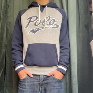 Grå och marinblå hoodie Polo Ralph Lauren - Riktig Snygg hoodie från Polo Ralph Lauren i grått och marinblått. Hoodien har inga defekter och ser nästan ny ut! Modellen på bilden är runt 175 cm. Skriv om ni har några fler frågor!