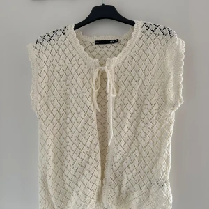 Vit stickad väst  - Superfin vit stickad väst från Lager157 med snyggt hålmönster och knytning framtill. Aldrig använd. 