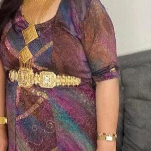Kurdisk klänning med glittriga detaljer - Unik långklänning i flera färger som lila, blå, brun och guld. Klänningen har glittriga inslag och abstrakt mönster. Smycken ej ingår. 