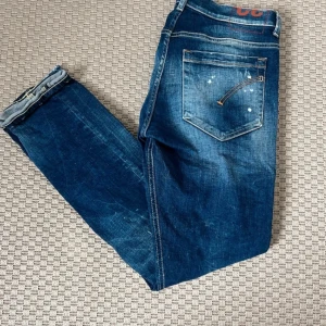 Blå skinny jeans från Dondup George - Snygga blå jeans från Dondup med slitningar och hål på knäna för en cool, avslappnad look. Jeansen har klassisk femficksdesign, smal passform och är tillverkade i mjukt denim. Perfekta för dig som gillar streetstyle och italiensk design.