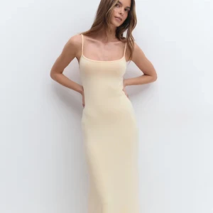 Ljusbeige långklänning med smala axelband - Supersnygg långklänning i ljusbeige med smala axelband och figurnära passform. Enkel och stilren design som ger en clean look. Perfekt för dig som gillar minimalistiskt mode och vill ha en klänning som känns både trendig och tidlös.