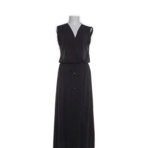 Svart långklänning från Lindex - Svart ärmlös långklänning från Lindex med v-ringning och omlott-look framtill. Klänningen har knyt i midjan för en snygg passform och är tillverkad i mjukt material med modal, polyester och elastan. Perfekt för dig som gillar stilren och enkel design.