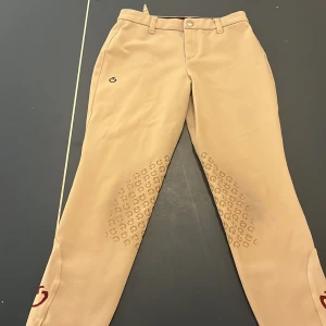 Vita ridbyxor från Cavalleria Toscana - Snygga vita ridbyxor från Cavalleria Toscana med silikonprint på insidan av benen för extra grepp. Byxorna har bälteshällor, knapp och dragkedja framtill samt diskret logga på låret. Tillverkade i stretchigt material för bästa komfort.