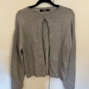 Grå kofta från BikBok  - Enkel och stilren grå kofta från BikBok i storlek XS. Koftan är stickad, har rund halsringning och stängs med en knapp upptill. Perfekt att slänga över en topp för en chill look. Långärmad och mjuk i materialet. Oanvänd