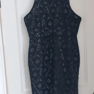 Svart  spetsklänning från H&M - Supersnygg svart  klänning från H&M med blommigt spetsmönster och rund halsringning. Klänningen är ärmlös och har en figurnära passform. Perfekt för dig som vill ha en elegant look med lite extra detaljer.