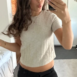 Beige ribbad topp från Zara - Superfin beige ribbad topp från Zara med korta ärmar och rund halsringning. Tröjan är i mycket fint skick och är sparsamt använd. Köparen står för frakten. Garderobrensar så kolla gärna in andra plagg!