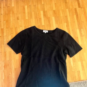 Svart t-shirt i kashmir från Davida - En svart t-shirt från Davida i mjuk kashmir. Klassisk rund halsringning och korta ärmar. Perfekt för dig som gillar en enkel men lyxig stil. Passar till allt och känns superbekväm mot huden.