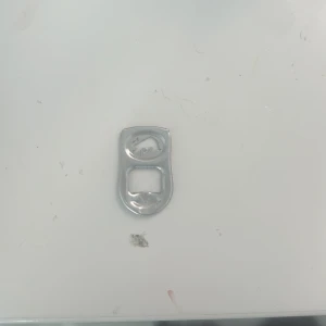 Redbulll  - Bilderna visar en aluminiumburkflik, vanligtvis använd för att öppna dryckesburkar. Produkten är inte elektronik och har inga synliga elektroniska komponenter, funktioner eller märkning. Inga defekter eller slitage utöver normalt bruk syns.