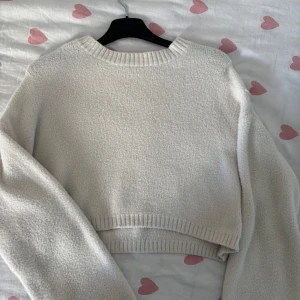 Vit croppad stickad tröja Bershka - Supermysig vit croppad stickad tröja från Bershka. Tröjan har lång ärm, ribbade muddar och en klassisk rund halsringning. Perfekt för lager-på-lager. Säljes i storlek S.