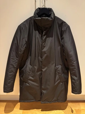 Svart vinterjacka These Glory Days - Svart vinterjacka från These Glory Days, jackan har två stora fickor framtill, dragkedja och långärmade ärmar. Materialet är syntet och polyester, perfekt för kalla dagar. Skandinavisk design med clean look.