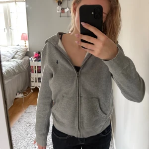 Grå zip hoodie från Polo Ralph Lauren - Grå hoodie från Polo Ralph Lauren i bra skick. Köpt för 1300kr. Den är i barnstorlek i L, men passar mig (jag har typ S i dom flesta kläderna) 