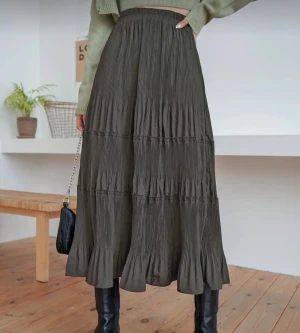 Mörkgrön  kjol -  mörkgrön långkjol med plisserad struktur och volangkant nertill. Kjolen har en flowy passform och resår i midjan för extra komfort. 