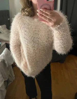 Ljusrosa fluffig stickad tröja - Supermysig ljusrosa stickad tröja med fluffig känsla och diskret mönster. Tröjan har lång ärm och ribbade muddar vid ärmslut och nederkant. Perfekt för dig som vill ha en söt och cozy vibe i garderoben.