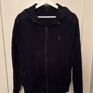 Polo Ralph Lauren Cardigan - Tja! Säljer nu denna Raplh Lauren Caridgan i strl M, snygg och unik, nypris ligger på ca 2799kr, defekt är att dragkedjan saknar ”drag huvudet” man drar i, ingen man lägger märke till dock! Hör av er vid frågor 