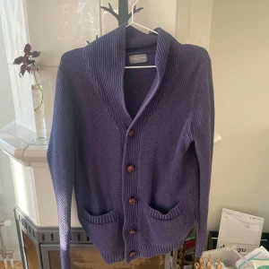 Lila  kofta från Grand Frank - Säljer en lila stickad kofta från Grand Frank i storlek medium. Koftan har grovstickad struktur, bred sjalkrage, två fickor framtill och snygga knappar. Perfekt för lager-på-lager och chill dagar. Strl M