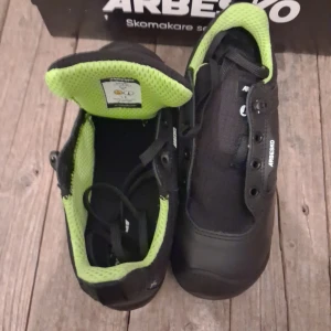 Svarta sneakers från Arbesko med grön sula - Snygga svarta sneakers från Arbesko med grön yttersula och detaljer. Skorna har snörning, rund tå och slitstark ovandel i syntet och textil. Insidan är fodrad med grönt meshmaterial för extra komfort. Perfekt för dig som vill ha både stil och funktion. Ny pris 2500 kr