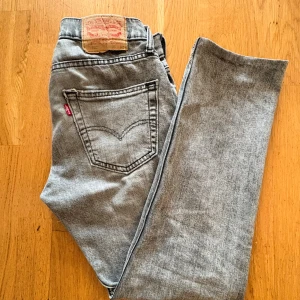 Levi's 501 Jeans - Ljusgrå Levi's 501 jeans med klassisk straight fit och femficksdesign. Jeansen har den ikoniska läderpatchen bak i midjan och är tillverkade i slitstarkt bomullsjeans. Perfekta för dig som gillar en tidlös och avslappnad look.