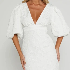 Showpo klänning - Supersnygg vit kort klänning med djup v-ringning och puffiga trekvartsärmar. Från showpo och i strl 34, bara använd på studentdagen!