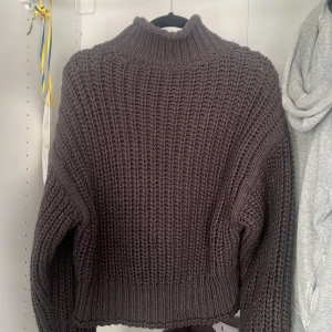 Brun stickad tröja från H&M - Säljer en chunky brun stickad tröja från H&M med hög krage och grov ribbad struktur. Tröjan har långärmade ärmar och en loose passform som ger en chill vibe. Perfekt för att hålla sig varm under kyliga dagar.