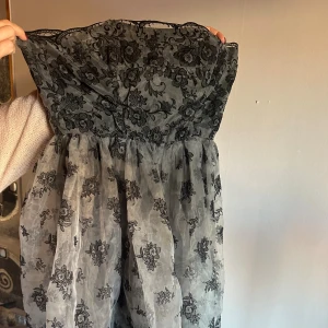 Svart blommig axelbandslös klänning  - Supersnygg off shoulder klänning i svart med  blommigt spetsmönster