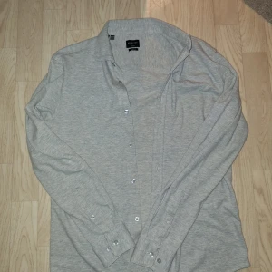 Ljusgrå kofta Selected Homme - Ljusgrå skjorta från Selected Homme i slim fit-modell med stretch. Skjortan har klassisk krage, långa ärmar och knäppning framtill. Tillverkad i mjuk bomullsblandning, perfekt för en clean och stilren look. Tveka inte på att höra av er vid frågor eller prisförslag‼️