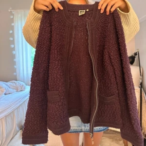 Jättesnygg mörklila teddyjacka  - Mysig mörklila/vinröd teddyjacka med grovstickad känsla och två fickor framtill. Jackan har en rak passform, rund halsringning och stängs med en silverfärgad dragkedja. Perfekt för lager-på-lager och chill höstoutfits.