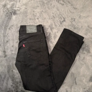 Levi's 511 jeans W29 L30 slim fit  - Svarta jeans från Levi's modell 511 med klassisk femficksdesign och röd Levi's-tag på bakfickan. Slim fit med rak siluett och normal midja. Tillverkade i bomull med lite stretch för extra komfort. Perfekt för dig som gillar en stilren och enkel look.