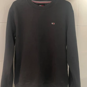 Mörkgrå sweatshirt från Tommy Hilfiger - Grå Tommy Hilfiger tröja i storlek M. Använd några få gånger och är i väldigt fint skick. Har inget tecken på slitage eller några defekter. Hör gärna av vid frågor!