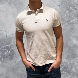 Ralph Lauren Piké vit - •Ralph Lauren Piké vitz Skick: 8/10, Inga skador. Storlek: 14/16 år~160-70 cm. Modell: 174 cm, 63 kg. Authentic: ✅. Hör av dig vid frågor eller funderingar, mvh Hessler’s;)