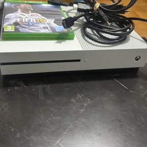 Xbox One S - Xbox One S i fint skick med två originalkontroller (vit och svart), kablar samt spelet FIFA 18. Konsolen har inga synliga skador.  Allt finns det är bara att koppla den och spela .  