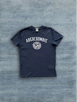 Abercrombie & Fitch T-shirt - Snygg marinblå T-shirt från Abercrombie & Fitch i mycket bra skick!