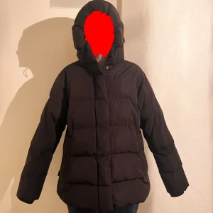 Svart pufferjacka från Zara med huva - Jag säljer en super fin svart pufferjacka från Zara i storlek M. Den är quiltad med breda kanaler och har både dragkedja och tryckknappar framtill. Den har en loose passform.