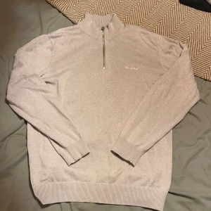 Beige half zip tröja från Bondelid - Snygg beige tröja från Bondelid med half zip och ribbad krage. Tröjan har långärmade ärmar och diskret broderad logga på bröstet. Perfekt för dig som gillar stilrena och klassiska plagg med modern touch!🙌🏼