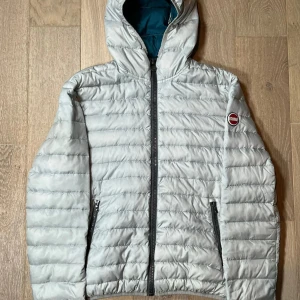 Ljusgrå dunjacka från Colmar - Säljer en ljusgrå dunjacka från Colmar med huva och svarta dragkedjor. Jackan har ett quiltat mönster och Colmar-logga på ärmen. Perfekt för kyliga dagar. Har lite defekter men de är lagade, därför så från ett ett super bra pris. Nypris ligger runt 5000kr vårt pris kommer att ligga på 999kr!!!!