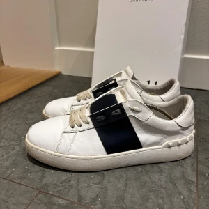 Valentino Garavani Open sneakers vit/blå - Säljer ett par Valentino Garavani Open sneakers. Passar storlek 41/42. Använda fåtal gånger och har bara en liten defekt där fram men inget som märks. Pris kan dirkuteras  