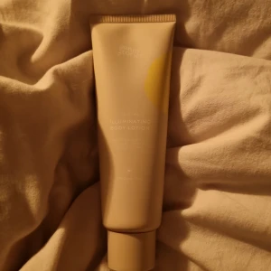 Sunny Stories Illuminating Body Lotion - Sunny Stories Illuminating Body Lotion är en self tan-lotion som ger en mjuk och naturlig solkysst look. Kommer i en beige tub med gul detalj, innehåller 125 ml och är vegansk. Perfekt för dig som vill ha glow och gradvis färg på kroppen.
