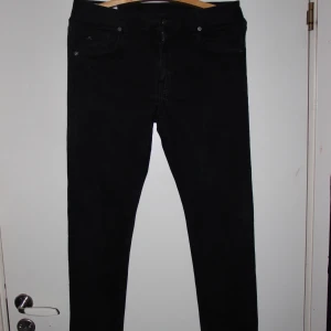 J.Lindeberg Jeans  - Svarta jeans från J.Lindeberg i klassisk femficksmodell. Byxorna har en slim passform och är tillverkade i ett mjukt bomullsmaterial med stretch. Snygg metallogo på myntfickan och diskreta detaljer. Perfekta för dig som gillar stilrena och enkla jeans.