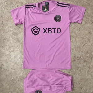 Inter Miami Messi fotbollströja rosa - Säljer en rosa fotbollströja från Inter Miami med Messi och nummer 10 på ryggen. Tröjan har korta ärmar, svarta detaljer och klubbmärke på bröstet. Materialet är lätt och andas, perfekt för match eller träning. Ingår matchande shorts med klubbmärke.