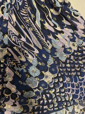 mönstrad klänning från Zadig & Voltaire - Snygg midokläning från Zadig & Voltaire med fjäder/blomigt mönster i marinblått, ljusblått, lila och guld. Klänningen har v-ringning, långärmade ärmar och är tillverkad i lyxig silke med metalliserade trådar. Flödande passform och coola detaljer som ger en unik look.