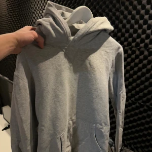 Grå hoodie från Polo Ralph Lauren - Snygg grå hoodie från Polo Ralph Lauren i storlek L. Tröjan har en klassisk huva, känguruficka framtill och långa ärmar. Perfekt för chill dagar och enkel att matcha med jeans eller joggers. Mjuk bomullskänsla och stilren look.