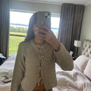 Beige kofta med rosetter från Gina Tricot - Superfin beige stickad kofta från Gina Tricot med långa ärmar och fyra söta rosetter framtill istället för knappar💕 Koftan är ribbstickad och har en rund halsringning. Perfekt för lager-på-lager under höst och vinter💕använd få tal gånger, hör av dig om det skulle vara något💕