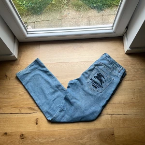 Burberry x Supreme ljusblå jeans - Ljusblå jeans från Burberry x Supreme med ikonisk broderad ryttare på bakfickan och liten logga fram. Klassisk femficksmodell i denim med raka ben och normal passform. Perfekt för dig som gillar streetwear och exklusiva samarbeten. Rekommend storlek W30/32 Mvh ItsForfits 🌟 autentisk men rätt så använd/ gott skick. Köpt från vestiare Collective länge sedan 